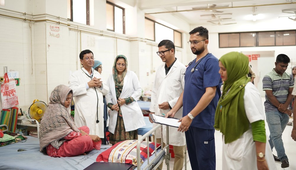 Consultants and nurses reviewing a patient at the bedside in the adult ward