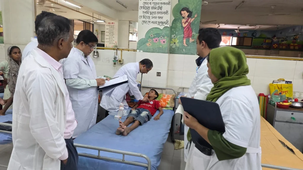 Consultant examining a child during a ward round in the paediatric cardiac ward, NICVD